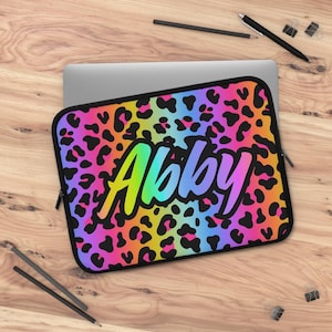 May include: A black laptop sleeve with a rainbow leopard print and the name "Abby" in a rainbow gradient font.
