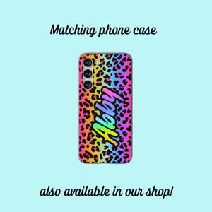 May include: A phone case with a leopard print background and a rainbow gradient design. The name "Abby" is written in a rainbow gradient font on the case.