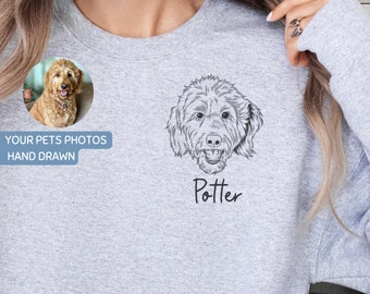 May include: A gray sweatshirt with a hand-drawn illustration of a dog with the name "Potter" printed below. The dog is a doodle with brown fur. The sweatshirt has a small image of the dog in the top left corner.