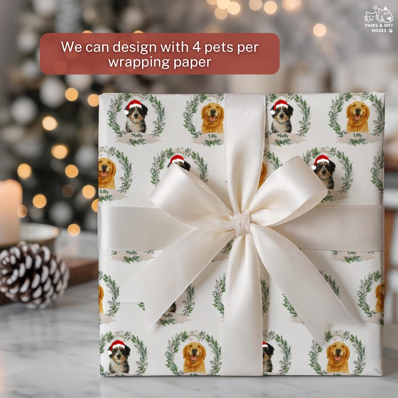 Op de afbeelding: Ingepakte cadeau met gepersonaliseerd cadeaupapier met hondenportretten in kransen, met de tekst "We can design with 4 pets per wrapping paper." Het cadeau is gebonden met een cr&egrave;mekleurig satijnen lint en strik.
