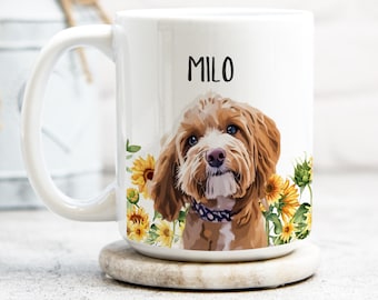 May include: White ceramic mug featuring a portrait of a dog named Milo, surrounded by sunflowers. The dog has brown fur, blue eyes, and a purple collar. The name "Milo" is printed in black above the dog's head. The mug has a large handle.