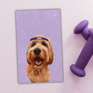 Może przedstawiać: Portret psa golden doodle w niebieskiej opasce z napisem "Milo" na tle lawendowego tła. Dwa fioletowe hantle w tle.