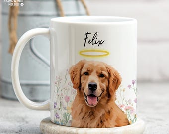 May include: White ceramic mug featuring a golden retriever illustration with a halo and the name "Felix". The mug is decorated with floral accents and sits on a marble coaster. The logo "Paws & Wet Noses" is visible.
