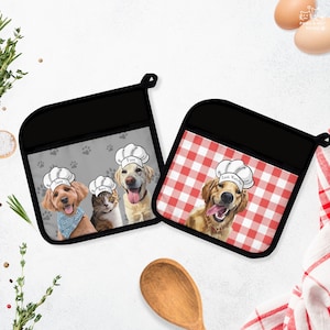May include: Two black oven mitts with dog and cat chef designs. One mitt has a red and white checkered pattern, the other has a gray background with paw prints. Each mitt features a different pet wearing a chef's hat.
