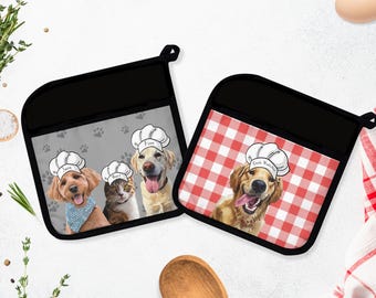 May include: Two black oven mitts with dog and cat chef designs. One mitt has a red and white checkered pattern, the other has a gray background with paw prints. Each mitt features a different pet wearing a chef's hat.