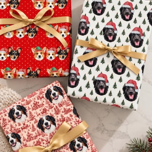 May include: Three rectangular gift boxes wrapped in patterned paper with gold ribbon bows. One red box features corgi faces, one white box shows black dogs in Santa hats with pine trees, and one cream box displays Bernese Mountain Dog faces.
