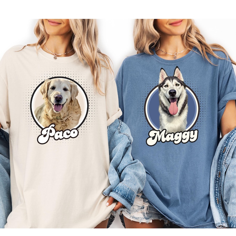 以下が含まれることがあります： クリーム色と青色の2枚のTシャツ。それぞれ円の中に犬の肖像画が描かれています。クリーム色のシャツには「Paco」という名前のゴールデンレトリバーが描かれています。青色のシャツには「Maggy」という名前のハスキーが描かれています。