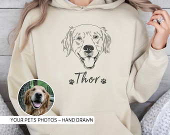 Puede incluir: Una sudadera con capucha beige con una ilustración dibujada a mano de un golden retriever con el nombre "Thor" impreso debajo. La sudadera tiene un bolsillo y una capucha con cordón. La imagen también incluye una foto más pequeña de un golden retriever.