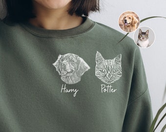 May include: A green sweatshirt with a white outline of a dog and a cat on the front. The dog is on the left and the cat is on the right. The dog is labeled "Harry" and the cat is labeled "Potter".