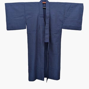 May include: A solid dark blue kimono featuring wide, rectangular sleeves and a structured collar. The garment is crafted from a textured fabric with a visible weave, displaying a straight-cut silhouette that hangs open at the front.