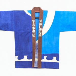 Peut inclure: Une veste happi bleue avec un col marron portant des caractères japonais blancs, un motif de vagues blanc le long de l'ourlet inférieur et des accents graphiques marron sur les manches. Le vêtement présente un design bicolore bleu et bleu clair.