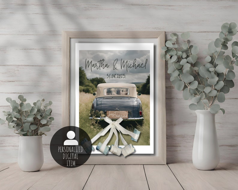 Charming wedding gift showcased in a wooden frame – a poster featuring wedding cars adorned with banknote-made cans. Two white vases on either side of the frame hold eucalyptus arrangements, adding an elegant touch to this unique piece.