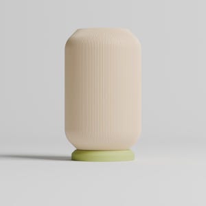 May include: A cream-colored ceramic vase with vertical ridges and a light green base.