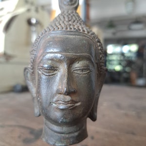 6,70 inch Bronze figure of a Buddha head from Thailand,. This patinated bronze sculpture depicts Siddhartha Gautama, the historical Buddha.