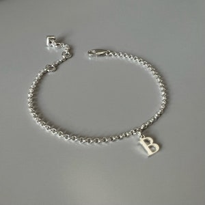 May include: A silver chain bracelet with a silver letter 'B' charm.