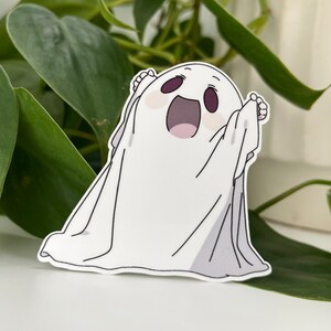 Op de afbeelding: Een witte geesten sticker met een glimlachend gezicht en uitgestrekte armen. De geest is getekend in een cartoon stijl met een eenvoudig ontwerp.
