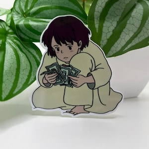 May include: A cartoon sticker of a young person with brown hair, wearing a light yellow robe, sitting and holding a stack of green bills.