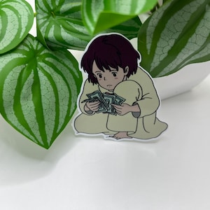 May include: A sticker of a cartoon girl with short brown hair, wearing a light brown robe, sitting on the floor and holding a stack of money in her hands.