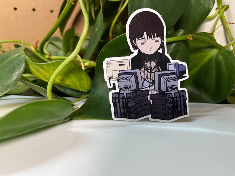 May include: A sticker featuring a cartoon character with black hair and a black and white outfit sitting in front of a stack of computers. The character is surrounded by wires and cables.