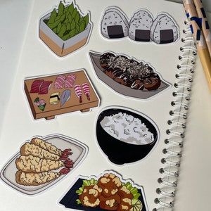 Op de afbeelding: Een set van negen stickers met Japans eten als thema. De stickers bevatten afbeeldingen van sushi, edamame, takoyaki, rijst, tempura en onigiri.