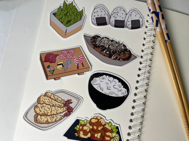 Op de afbeelding: Een set van negen stickers met Japans eten als thema. De stickers bevatten afbeeldingen van sushi, edamame, takoyaki, rijst, tempura en onigiri.