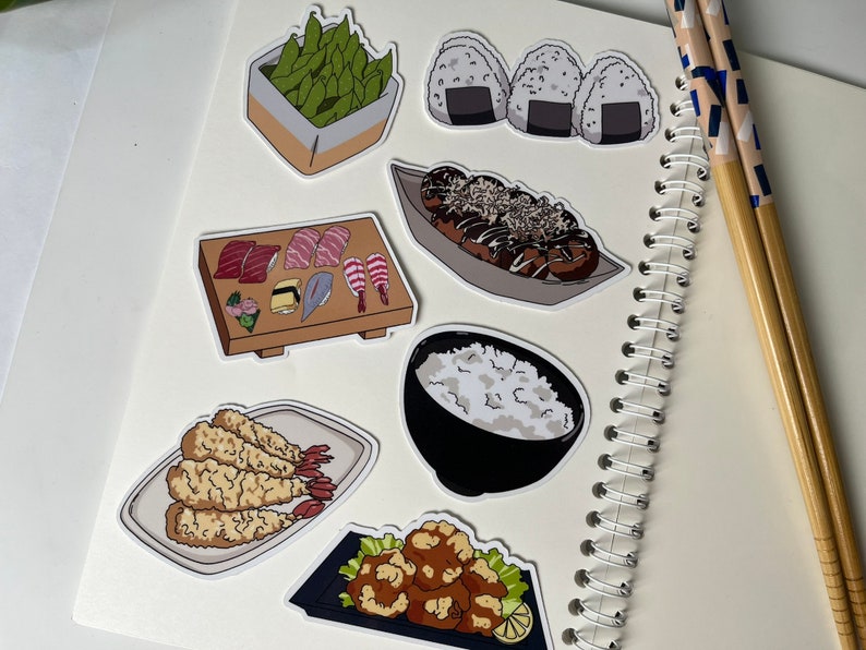 Op de afbeelding: Een set van negen stickers met een Japans eetthema. De stickers bevatten afbeeldingen van sushi, edamame, onigiri, takoyaki, tempura en rijst. De stickers zijn gedrukt op wit papier en hebben een glanzende afwerking.