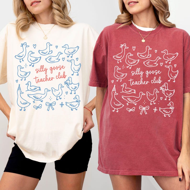 Puede incluir: Dos camisetas holgadas, una crema y otra roja, con un dise&ntilde;o caprichoso. Las camisetas muestran un patr&oacute;n de gansos de dibujos animados, corazones y lazos, con el texto "silly goose teacher club" en una fuente l&uacute;dica. Las camisetas son informales y c&oacute;modas.