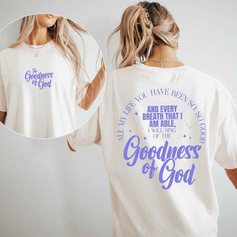 May include: Cream-colored t-shirt with the text "The Goodness of God" in a purple script on the front and back. The back of the shirt features a circular design with the phrase "All my life you have been so good" and more text.