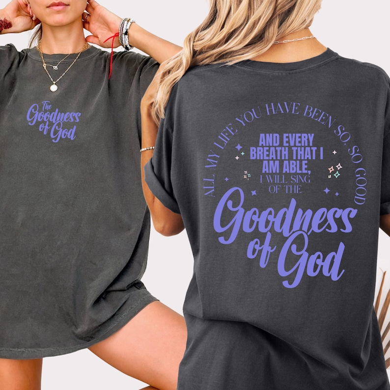 May include: Dark grey t-shirts with the text "Goodness of God" in a purple script. The back of the shirt has the text "All my life you have been so, so good" and "And every breath that I am able, I will sing of the Goodness of God."