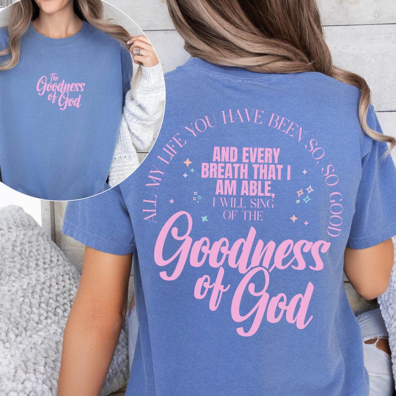 May include: A blue t-shirt with the text "The Goodness of God" in pink on the front and back. The back of the shirt also features the phrase "All my life you have been so, so good" in pink.