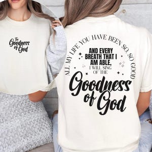 May include: Cream-colored t-shirt with the text "The Goodness of God" on the front and back. The back of the shirt features a circular design with the phrase "All my life you have been so good" and the words "Goodness of God".