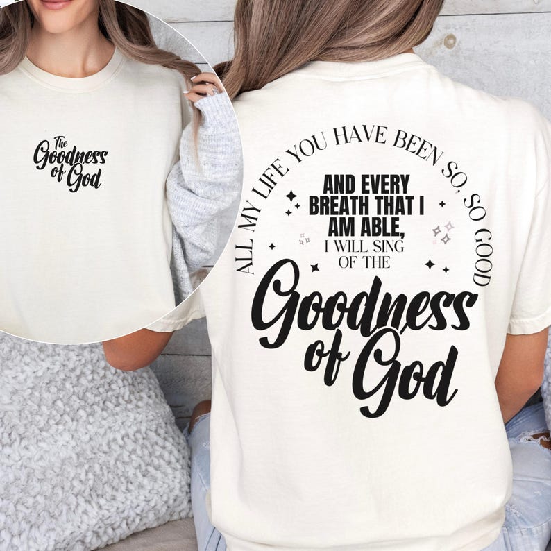 May include: Cream-colored t-shirt with the text "The Goodness of God" on the front and back. The back of the shirt features a circular design with the phrase "All my life you have been so good" and the words "Goodness of God".