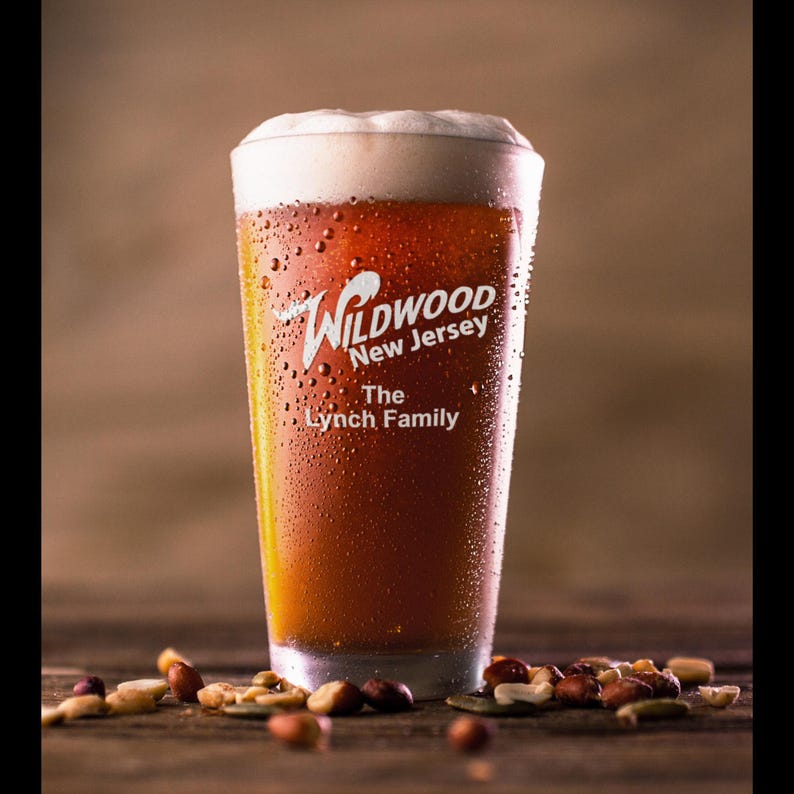 May include: A frosted glass beer mug with a white logo that reads "Wildwood New Jersey The Lynch Family". The mug is filled with a dark amber beer and condensation on the outside of the glass.
