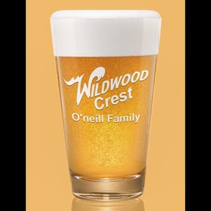 Peut inclure: Un verre transparent rempli de bi&egrave;re et surmont&eacute; d'une mousse blanche. Le verre porte les mots "Wildwood Crest" et "O'Neill Family" imprim&eacute;s en blanc. Le fond est de couleur orange.