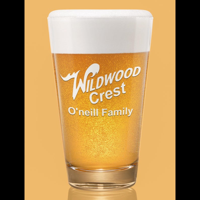 Peut inclure: Un verre transparent rempli de bi&egrave;re et surmont&eacute; d'une mousse blanche. Le verre porte les mots "Wildwood Crest" et "O'Neill Family" imprim&eacute;s en blanc. Le fond est de couleur orange.