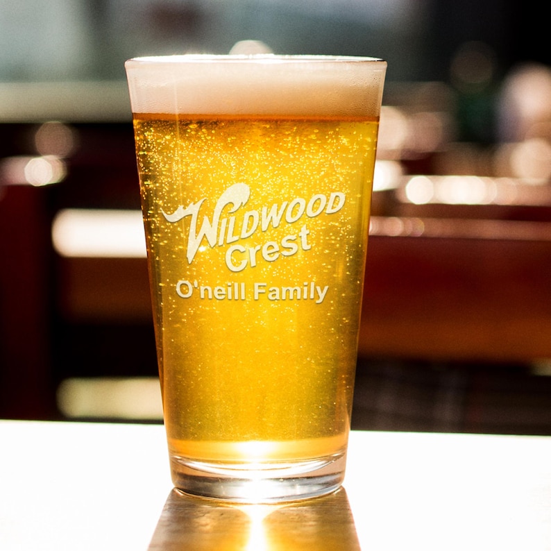 Peut inclure: Un verre &agrave; bi&egrave;re rempli de bi&egrave;re dor&eacute;e et surmont&eacute; d'une mousse. Le verre porte les mots "Wildwood Crest" et "O'neill Family". La bi&egrave;re est p&eacute;tillante et semble fra&icirc;che.