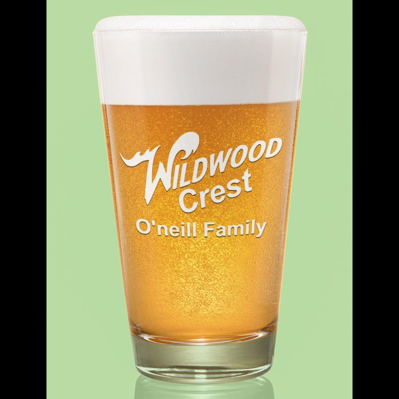 Peut inclure: Un verre &agrave; bi&egrave;re transparent rempli de bi&egrave;re et surmont&eacute; d'une mousse blanche. Le verre porte l'inscription blanche "Wildwood Crest" et "O'Neill Family". La bi&egrave;re est de couleur dor&eacute;e.