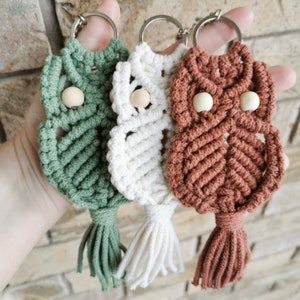 May include: Three handmade macrame owl keychains with wooden beads. The owls are green, white, and brown.