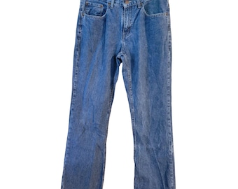 May include: Blue denim jeans with a classic five-pocket design. The jeans are hanging on a white hanger. The jeans have a straight leg fit and a button and zipper closure.