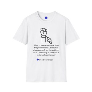 May include: White t-shirt featuring a black graphic of a fist breaking chains, with the quote "Liberty has never come from the government..." by Woodrow Wilson. A blue circle is below the quote.