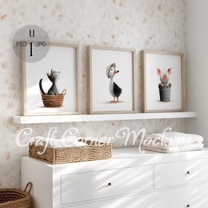 Può includere: Tre stampe artistiche incorniciate con illustrazioni ad acquerello: un gatto grigio in un cestino, un'anatra con un cappello e un maiale in un secchio. Le stampe sono su una mensola bianca contro un muro strutturato.
