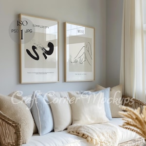 May include: Two framed minimalist art prints on a white wall above a white couch with beige and light blue throw pillows. The print on the left has a black abstract design and the text "SIMPLICITY" and the print on the right has a black line drawing of a person and the text "MUSE".
