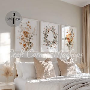 May include: Three framed watercolor prints of floral arrangements in shades of brown, orange, and green. The prints are hanging on a white wall above a white bed with beige pillows.
