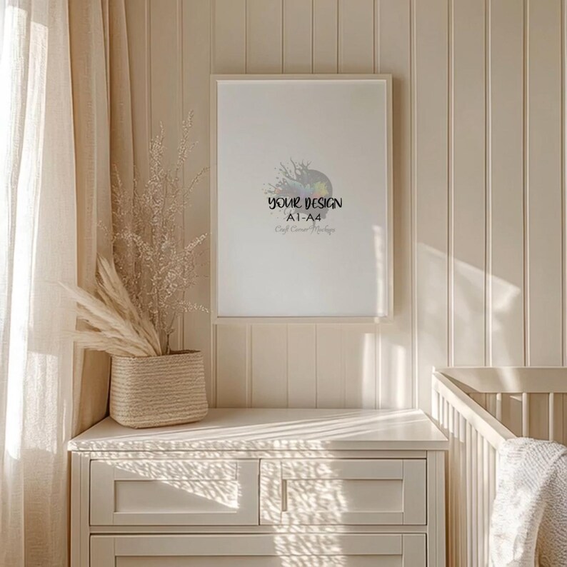May include: A framed white poster with the text "YOUR DESIGN A1-A4 Craft Corner Mockup" hangs on a cream-colored wall. A woven basket with dried plants sits on a matching cream-colored dresser. A crib is visible in the background.