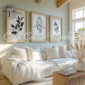 May include: A white couch with white throw pillows and a white blanket in a living room with a wicker coffee table and three black and white line art prints on the wall. The prints feature a woman, a plant, and a flower.