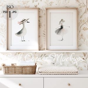 Könnte beinhalten: Zwei gerahmte Aquarelldrucke. Einer zeigt eine Möwe mit Hut und rosa Schleife. Der andere zeigt eine Mäuseballerina in einem Tutu. Die Drucke werden über einer weißen Kommode mit einem Weidenkorb und einer gefalteten Decke ausgestellt.