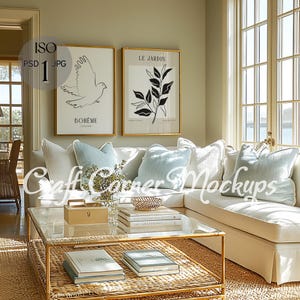 Puede incluir: Una sala de estar con un sofá blanco, cojines azul claro y una mesa de centro de cristal. Dos impresiones artísticas enmarcadas cuelgan sobre el sofá, una con una ilustración de paloma y la palabra "BOHEME", la otra con un diseño botánico y las palabras "LE JARDIN".