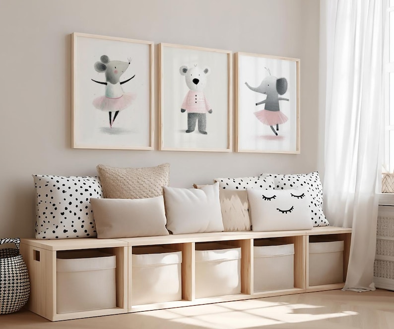 May include: Three framed wall art prints featuring watercolor illustrations of a mouse in a pink tutu, a bear in a striped shirt, and an elephant in a pink tutu, displayed above a light wood storage bench with five fabric bins and pillows.