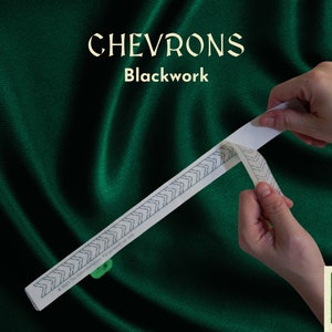 Op de afbeelding: Een wit transferblad met een zwart chevron-patroon. Het blad wordt van een dragerblad getrokken. De tekst "CHEVRONS Blackwork" is zichtbaar bovenaan de afbeelding.