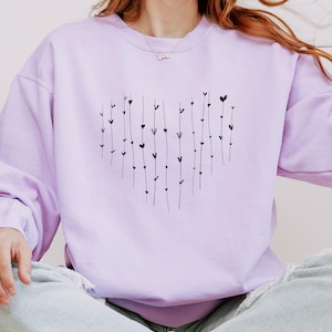 May include: A lavender sweatshirt with a black heart design made of small hearts and lines. The sweatshirt is a crew neck style.